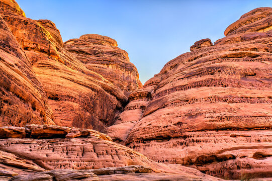 Dramatic red sandstone cliffs and unique rock formations at Jabal Ithlib in the ancient Nabataean site of Hegra, Al Ula, Saudi Arabia.