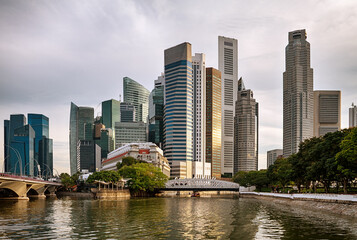 Modern city skyline with tall skyscrapers, river reflections, and urban waterfront architecture in Singapore during soft evening light. © irakite