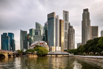 Modern city skyline with tall skyscrapers, river reflections, and urban waterfront architecture in Singapore during soft evening light. © irakite