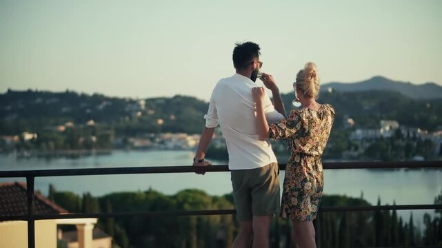 Romantic Travelers  Enjoying Beautiful Sea View from Terrace. Travelers Celebrating Holiday with Drinks