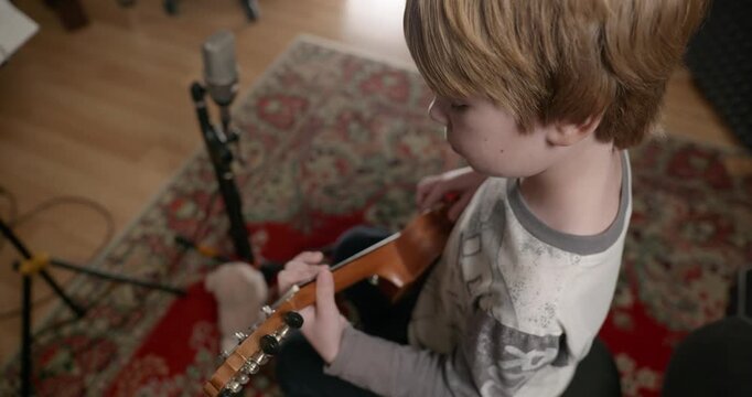 Boy Play Music on Ukulele Instrument in Home Studio. 4K 10-bit