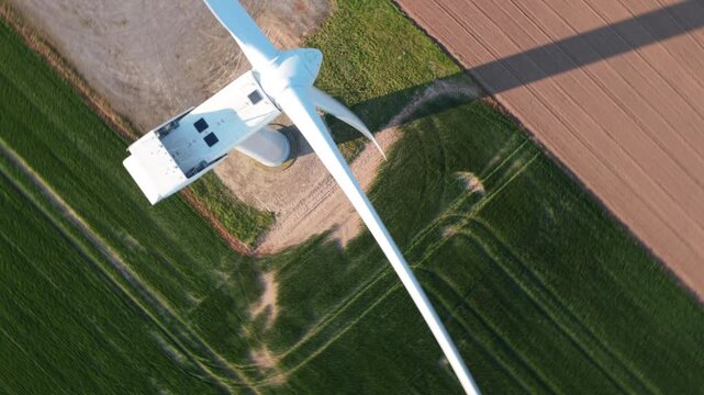 Aerial view of a wind turbine nacelle and rotating blades at Keadby Wind Farm over lush green agricultural fields in Keadby, England, United Kingdom.