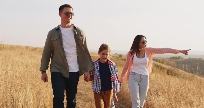 Family walking outdoors, parents and children together. Happy faces explore a meadow trail, enjoying nature, leisure, and travel, bonding on a carefree hike. Concept: family happiness in nature.