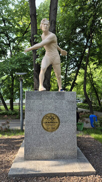 A statue of the Romanian Olympic discus champion Lia Manoliu standing on a stone pedestal in a lush green park. Picture taken on May 7, 2026 in Bucharest, Romania.