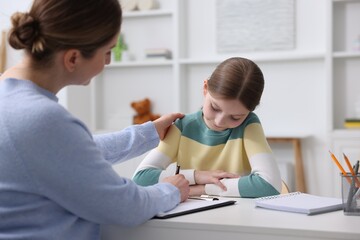 Obraz premium Professional child psychologist working with girl at white table indoors