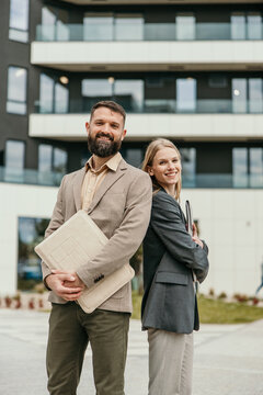Business partners smiling and standing outdoors at office building
