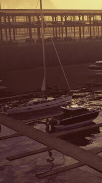 Boats move on water close to a dock during the early morning. Soft light shows reflections on the water. The marina is busy as the day begins.