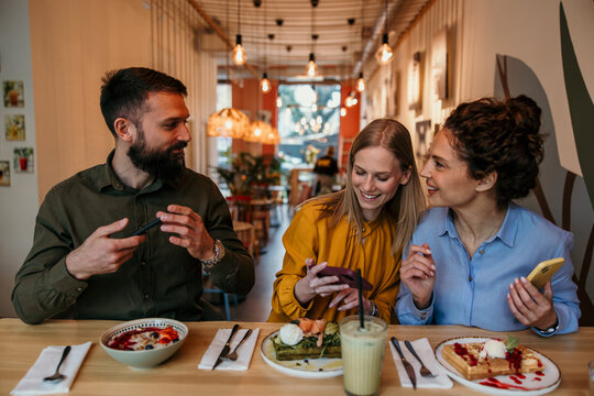 Friends enjoying breakfast taking pictures with smartphones