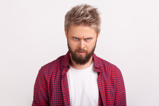 Confused bearded man looking directly at camera with slightly furrowed brows uncertain expression posing isolated over white background