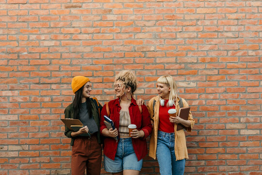 Young female student friends enjoying coffee on campus