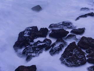 Ocean waves crashing around coastal rocks long exposure © Paul
