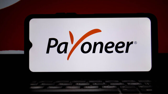 Payoneer logo displayed on a smartphone screen, with a laptop keyboard in the foreground, representing global payment solutions