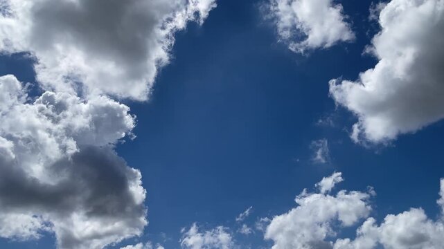 Skyward Gaze: Capture the serene beauty of a radiant blue sky, framed by fluffy, ethereal clouds drifting lazily across the expanse. 