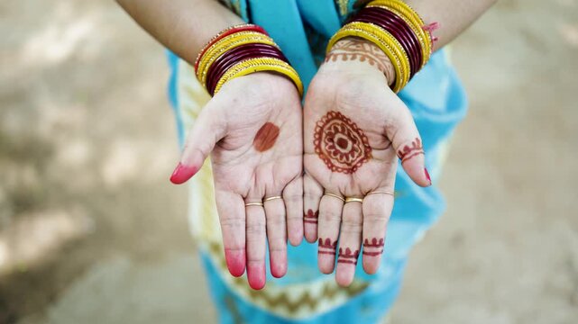 indian woman displaying mehndi patterns on palms with traditional jewelry and bangles on festival