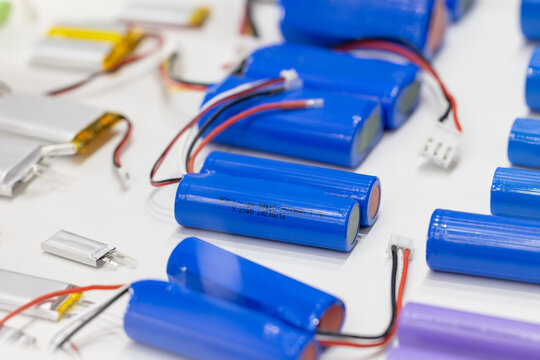 Blue 18650 lithium ion battery packs with labels and connectors. Rechargeable power cells for high performance electronics. Group of energy storage components on white surface