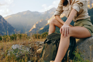Naklejka premium Cheerful woman outdoors, resting on a rock in a mountain landscape, wearing casual hiking clothes, sunlit moment, relaxed posture, natural tones, expansive scenery. Calm.
