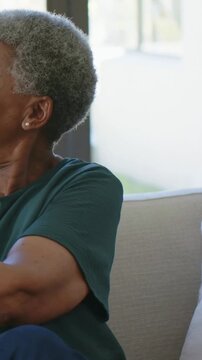 Vertical video: Approaching from right, child hugging woman in green top, showing affection on sofa