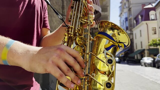 Male fingers of musician play the saxophone on summer day. Natural light reflects off metal surface, highlighting movement and rhythm. Scene captures live urban music and atmosphere street performance