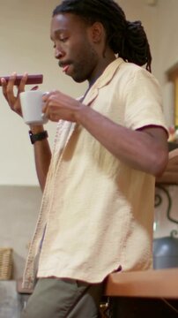 Vertical video: After sipping man in shirt in kitchen raising phone to leave message with white mug