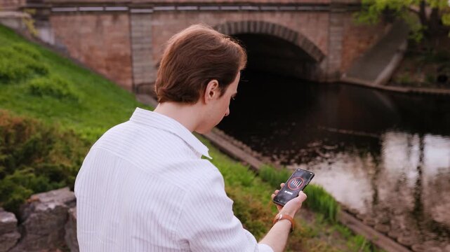 A man experiences a poor connection and cellular network loss while using his smartphone near a bridge. 4K footage highlighting an internet outage and no signal error. High quality 