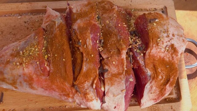 A hand is sprinkling seasoning on a leg of lamb for further roasting. Top view. High quality 4k footage
