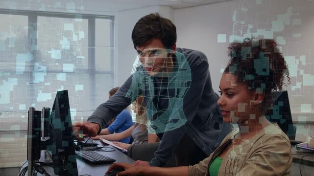 Tutor leaning over workstation, pointing at monitor and reviewing 3D skull hologram for education