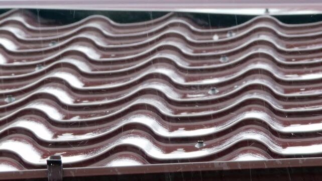 Heavy summer rain pouring on wavy roof tiles
