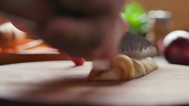 A knife slices along a parsley root on a wooden cutting board. Preparing roasted vegetables for a classic Sunday roast. Fresh ingredients and home cooking at its best.
