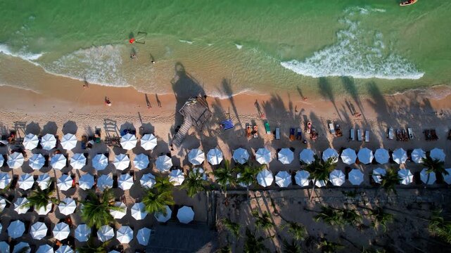 Aerial video of the amazing emerald water white sand Sao Beach with lively water sports, tourists, cabanas and sun umbrellas, beach bar and parasailing. Hot sunny day with long waves on Phu Quoc Islan
