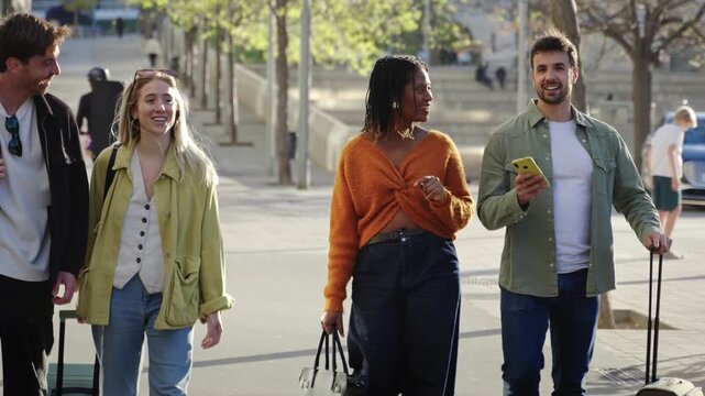 Group of young tourist friends walking in the city, carrying suitcases, enjoying holiday during weekend trip