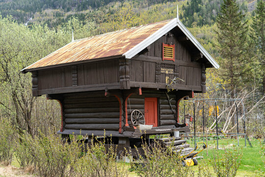 Authentic traditional Norwegian stabbur (raised wooden storehouse) in the rural landscape of Telemark, Norway. Historic dark timber architecture.
