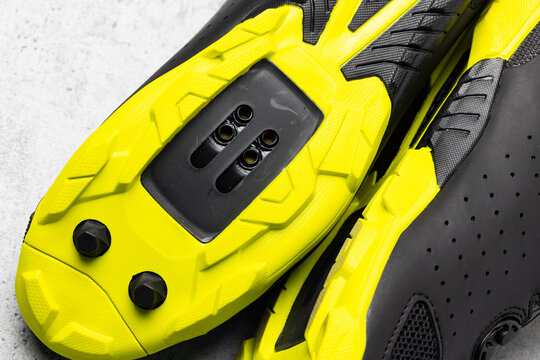 Yellow soles of brand new SPD cycling shoes on gray background. Mountain bike cycling shoes shot with flash light.