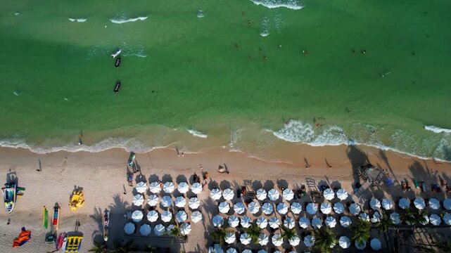 Aerial video of the amazing emerald water white sand Sao Beach with lively water sports, tourists, cabanas and sun umbrellas, beach bar and parasailing. Hot sunny day with long waves on Phu Quoc Islan