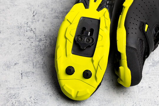 Yellow soles of brand new SPD cycling shoes on gray background. Mountain bike cycling shoes shot with flash light.