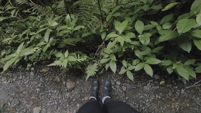 A point of view scene shows black boots and black leggings standing on a gravel trail in El Yunque rainforest in Puerto Rico.