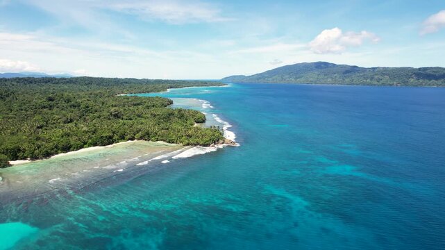 Aerial view of Mushu Island featuring dense tropical vegetation, white sandy beaches, and vibrant coral reefs in Wewak District, East Sepik Province, Papua New Guinea.