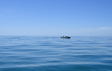 Fototapeta premium Small Motorboat with Passengers Cruising on Calm Blue Ocean Water