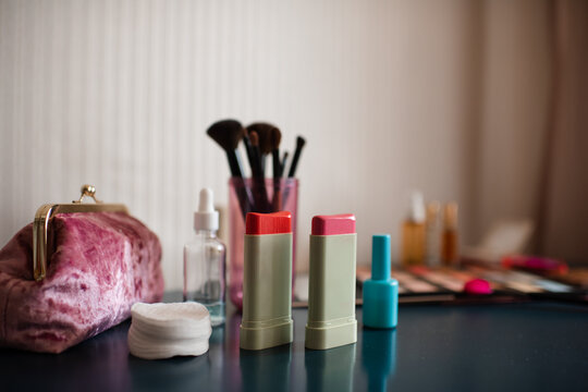Set of cosmetic products with blush in sticks on table close up. Make up collection with brushes.
