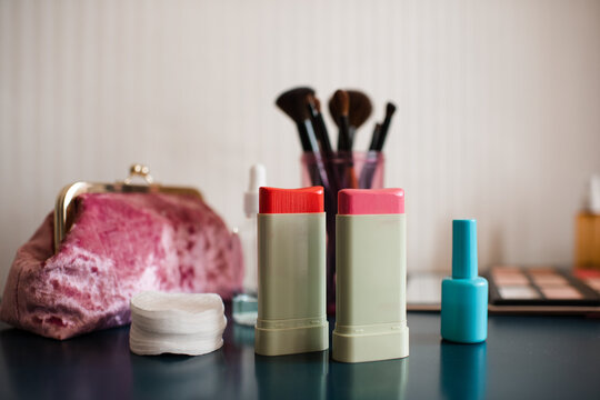 Set of cosmetic products with blush in sticks on table close up. Make up collection with brushes.