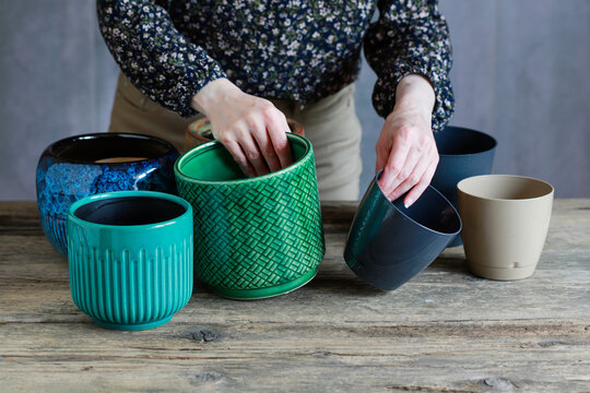 A woman checking if plastic liners fit the size of decorative ceramic flower pot covers.