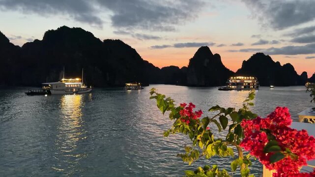 Cruise ships anchored in Ha Long Bay at twilight with limestone karst formations, blooming bougainvillea, golden reflection on tranquil water