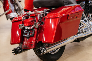 Fototapeta premium Detailed close-up shot captures rear section of a gleaming red motorcycle. Features include spacious saddlebags, integrated taillight with amber turn signals, and polished chrome exhaust system.