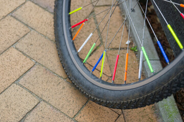 Fototapeta premium Bicycle wheel with colorful spoke reflectors on pavement outdoors