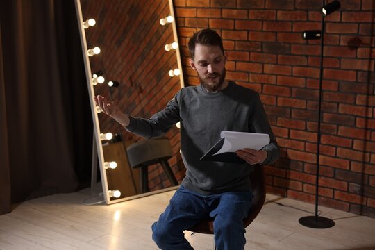 Actor with script rehearsing his lines in dressing room