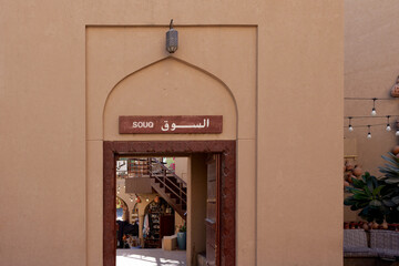 Obraz premium Traditional souq entrance in Nizwa featuring beige Omani architecture, Arabic sign, arched doorway and authentic market atmosphere in historic city center