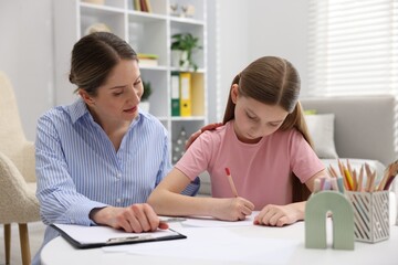 Obraz premium Girl drawing at white table during consultation with professional child psychologist indoors