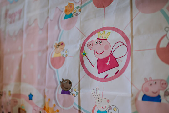 Peppa Pig themed birthday decoration featuring colorful characters and playful designs on a pink backdrop for children's celebrations