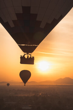 Hot air balloons floating over Teotihuacan Mexico at sunrise with silhouettes against a vibrant orange sky