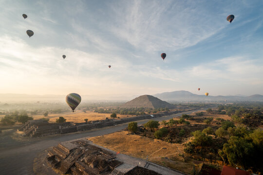 Hot air balloons floating over Teotihuacan pyramids at sunrise in Mexico with scenic landscape and clear sky