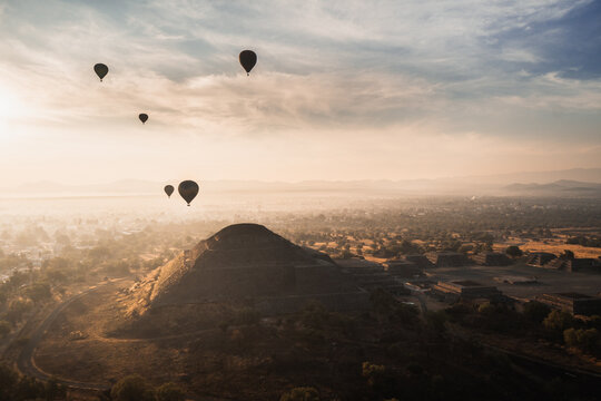 Hot air balloons floating over Teotihuacan pyramids at sunrise in Mexico with scenic landscape and ancient architecture